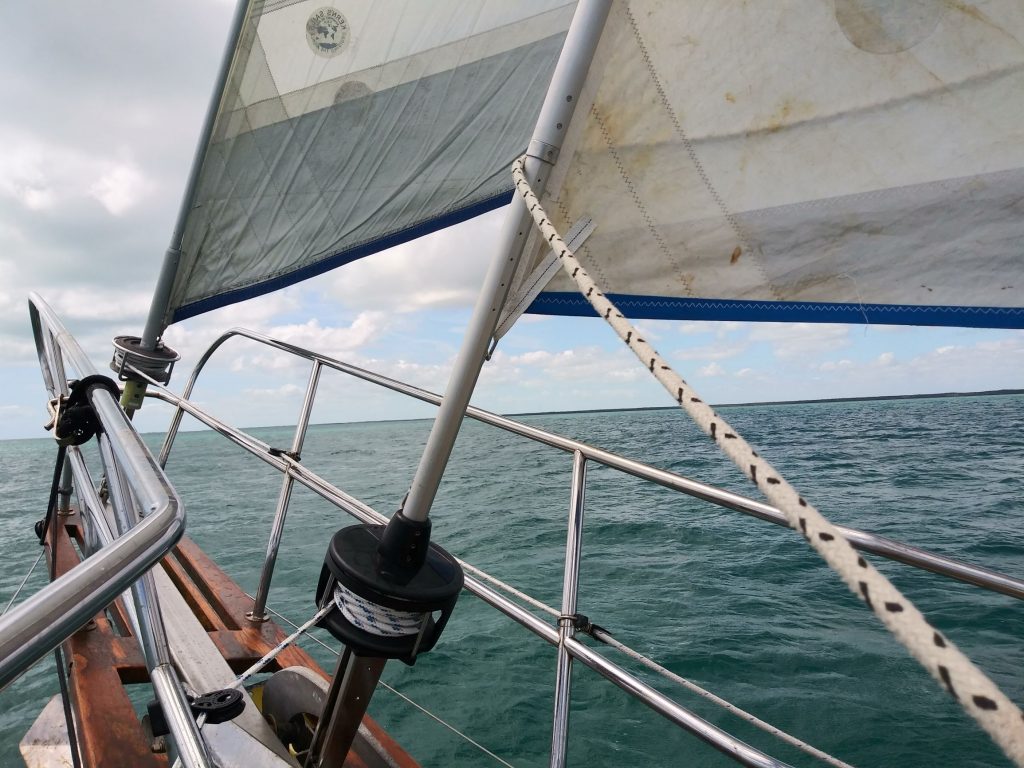 view over water from sailboat bow, two headsails 
