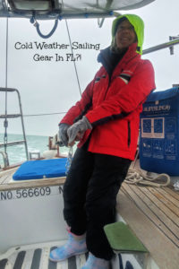 Julie at the tiller with cold weather gear on including mittens sailing in FL