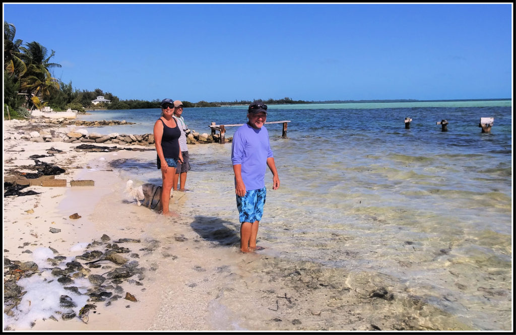 cruising friends standing in the shallow water to cool off after a hike on the island