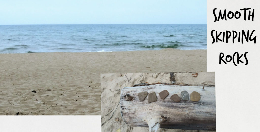 skipping rocks lined up on a log, beach and water of Lake Michigan