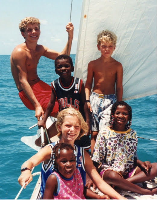 6 kids on bow of sailboat 
