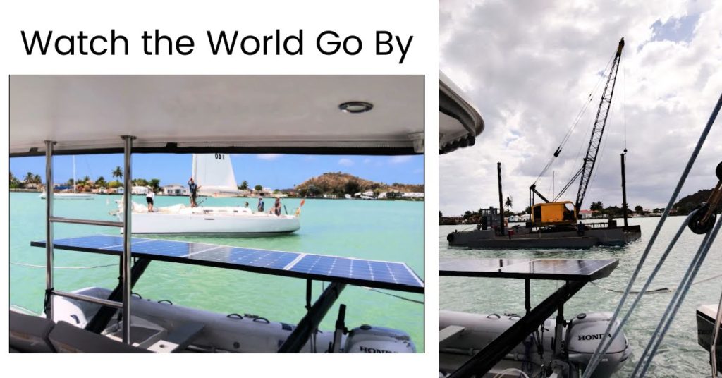 View from stern of sailboat of sailing school with students onboard and a dredging crane 