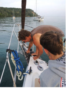 man bringing anchor onto the bow of the boat 