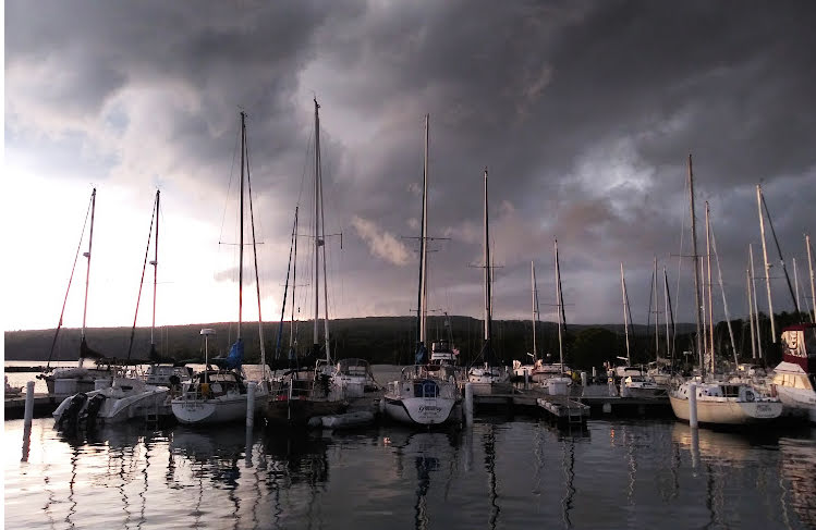 sailboats at dock with dark stormy sky