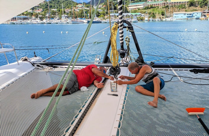 two men working on a boat project on the tramp of a catamaran 
