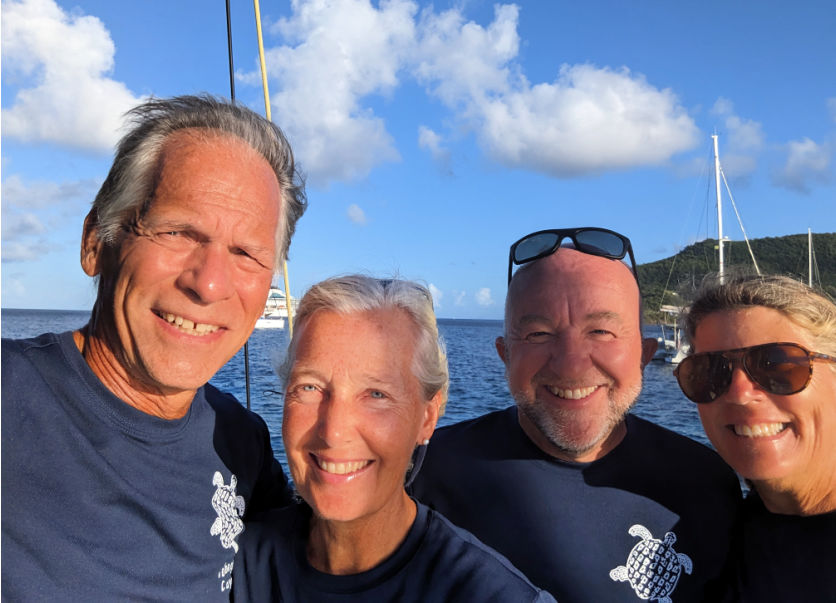 picture of four sailors on sailboat with matching blue shirts 
