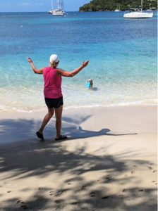 woman playing with dog at beach, dog with frisbee in mouth 