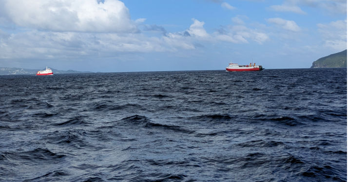 two ferries crossing paths on the water between islands 