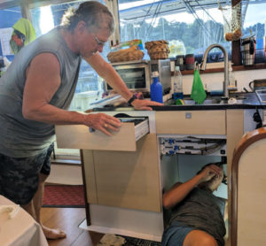 two men working on a boat project under and near the galley sink 