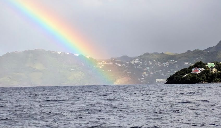 picture of rainbow over water with land in background