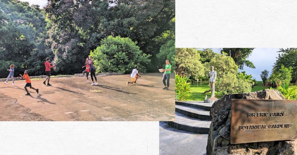 children exercising on a cement slab among the trees, statue and sign at sir eric gairy garden 