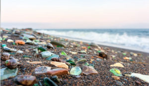 beach scene with sea glass scattered along the rocks on the beach, waves rolling in 