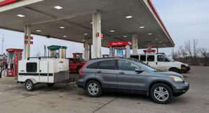 car and small trailer at a gas station during a road trip 