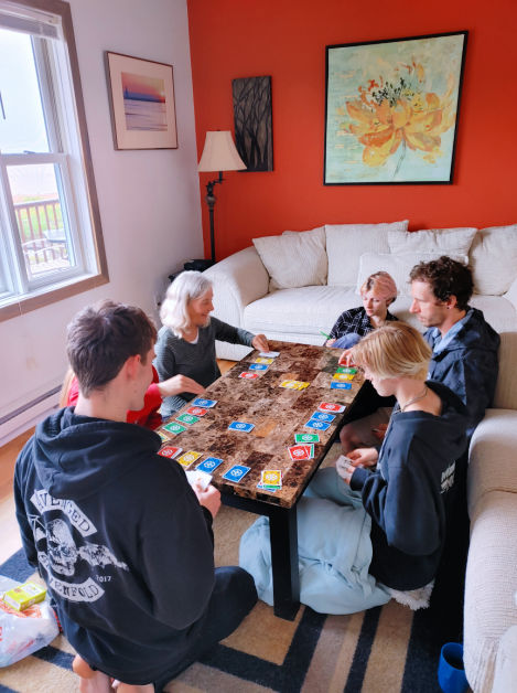 family group playing board game on living room floor of cabin 