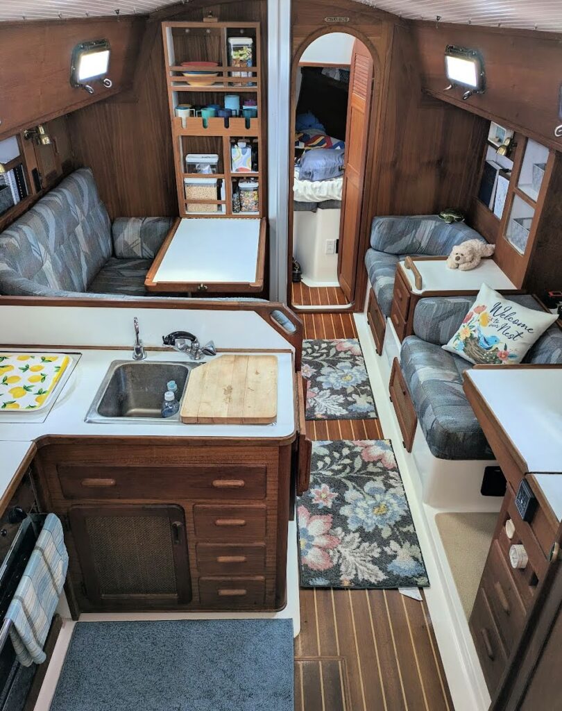 cabin of sailboat with rugs on floor, storage containers, throw pillow, stuffed animals to make it look like a home
