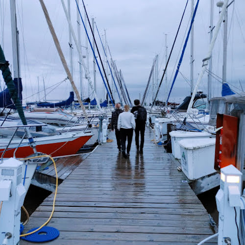 three young adults walking down marina dock with sailboats on either side