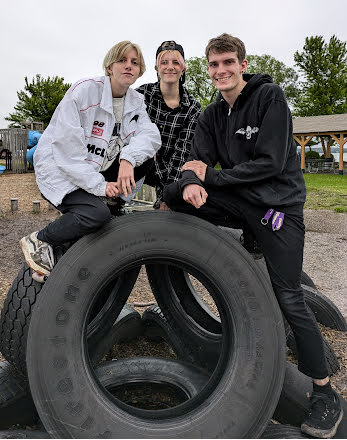 3 young adults at playground on group of tires 