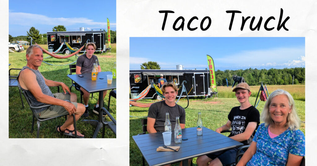 grandparents and teen at table with taco food truck in background in a big lawn area 