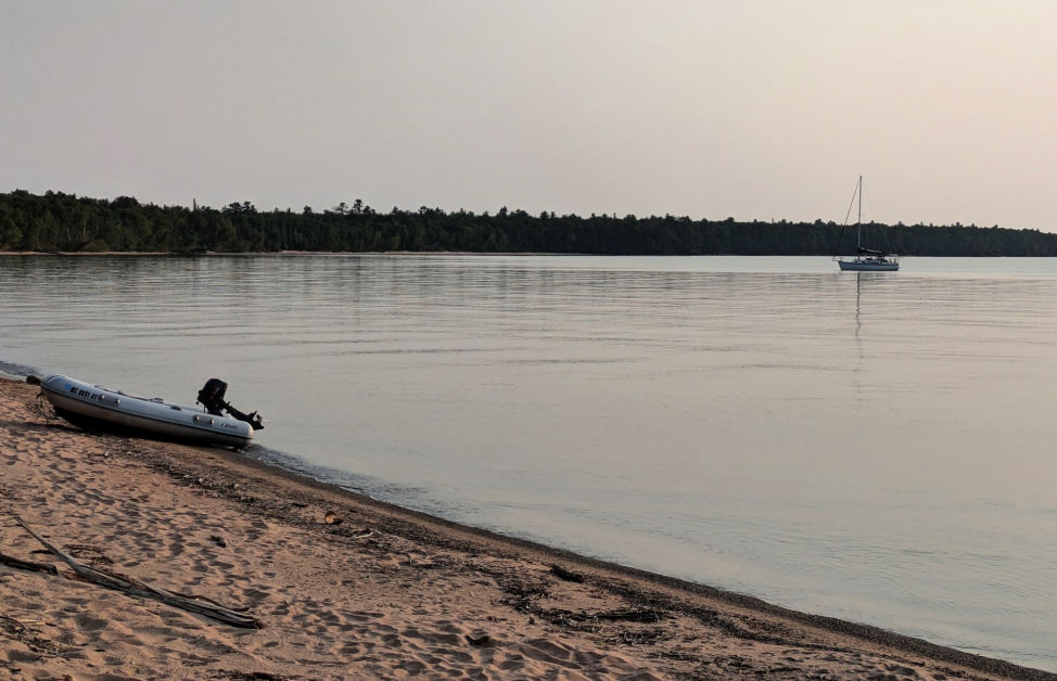 sailboat at anchor on calm lake superior with island in background 