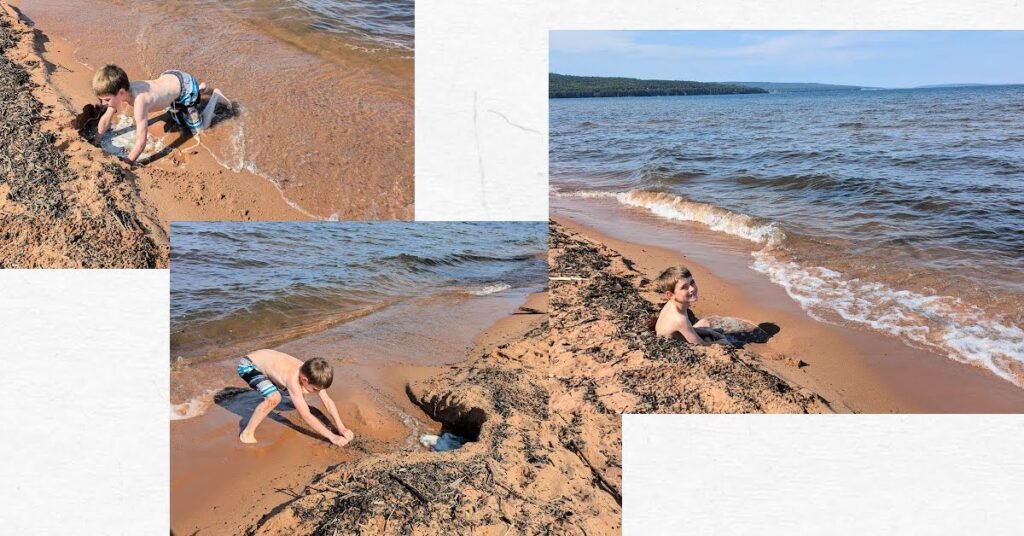 boy digging in the sane at waters edge, boy sitting in hole in the sand at waters edge 