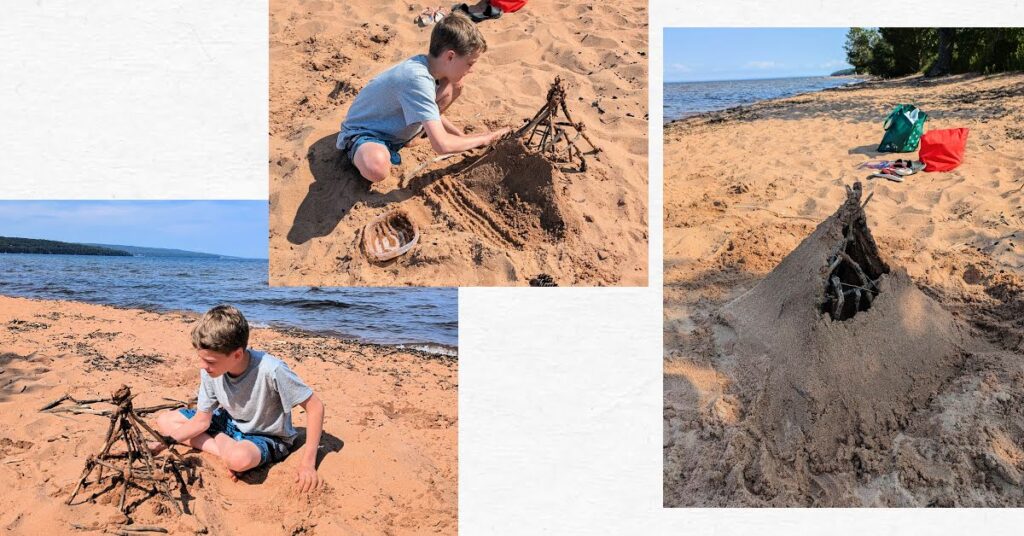 boy making a sand sculpture using sticks and wet sand 