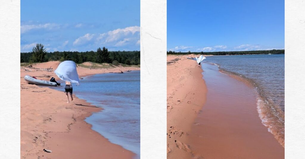 boy running down the beach with a large towel as a cape 