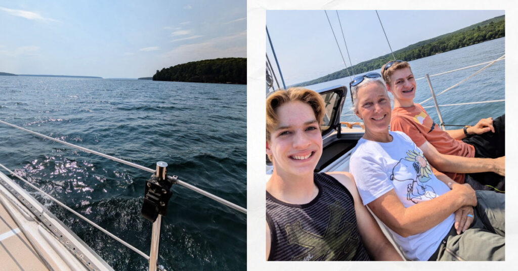 grandma and teen grandsons sitting on bow of boat with island in the background, view from side of sailboat of water and islands and blue skies 