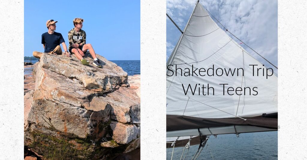 two teen boys sitting on a big rock on lake superior, sail in the sky