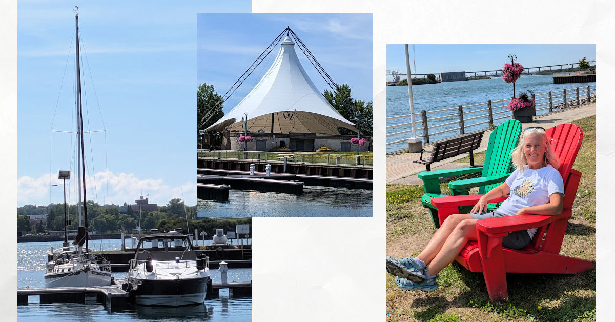 women in red chair overlooking st marys river, roberta bondar marina with boats at dock and tent on lawn 