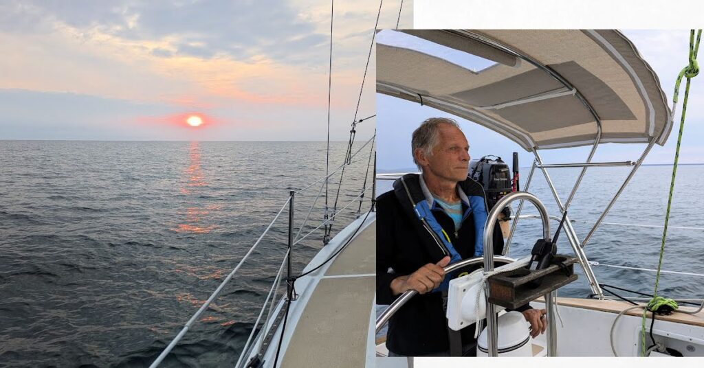 man at wheel of sailboat at sunrise, sun rising over lake superior from sailboat 