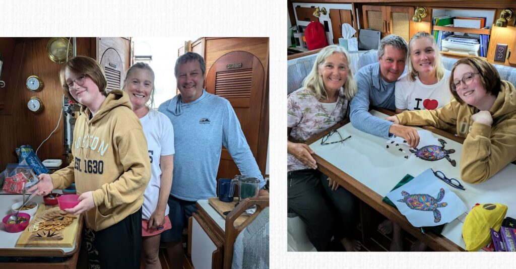 couples and teen in sailboat cabin getting food on charcuterie board and working on turtle jigsaw puzzle at dining table