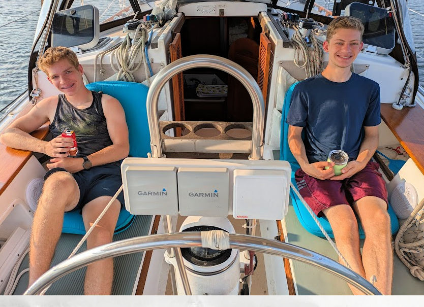 teen boys relaxing in cockpit of sailboat 
