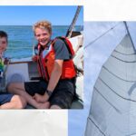 boys in lifejackets in cockpit of sailboat, reefed mainsail full of wind with blue sky