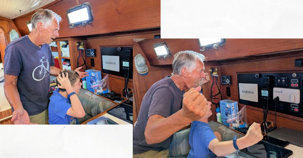 grandpa and grandson monitoring the solar and batteries while inside sailboat cabin 
