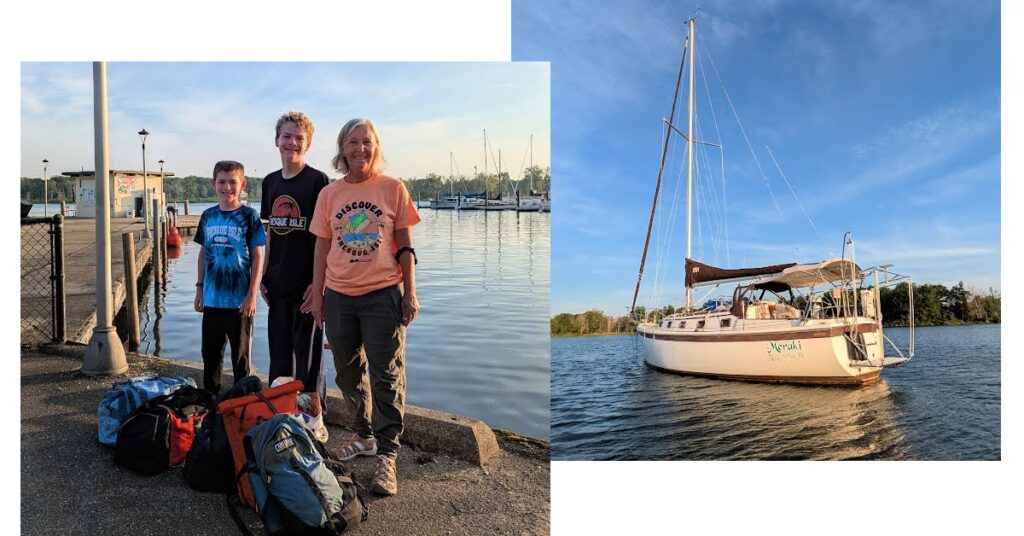 grandma and grandsons with duffel bags on shore, sailboat at anchor in anchorage 
