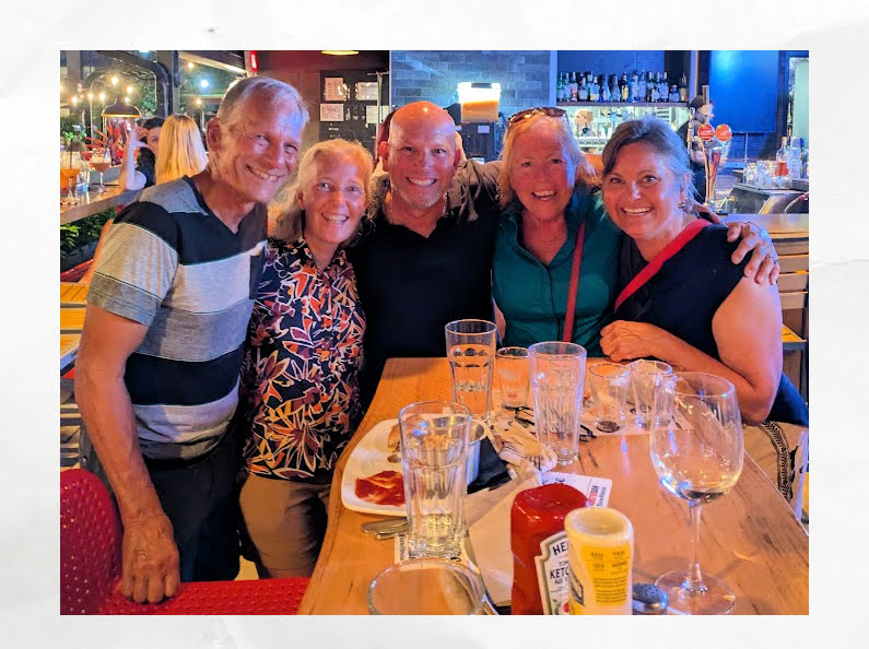 group of frineds hugging and smiling after eating at a restaurant 
