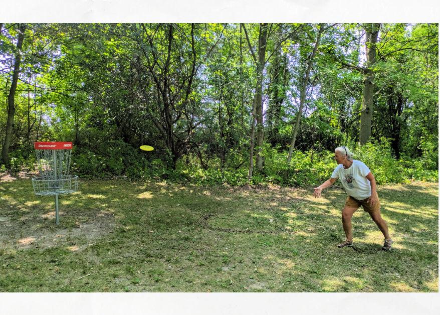 woman playing disc golf on wooded course
