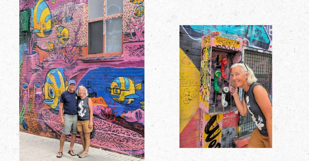 couple in front of mural of fish, woman near street art of old fashioned phone booth 