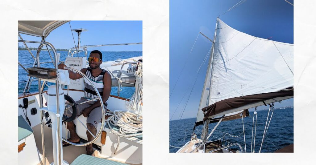 young man at wheel of sailboat, sails up with blue sky 