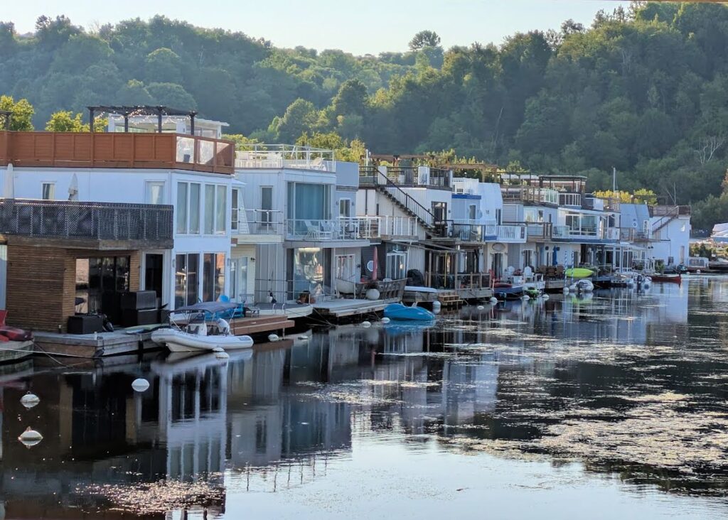 floating homes in Bluffer's Park Marina on Lake Ontario, green trees on hill in background 
