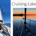 sailboat under sail and bow of boat at anchor with orange sunset