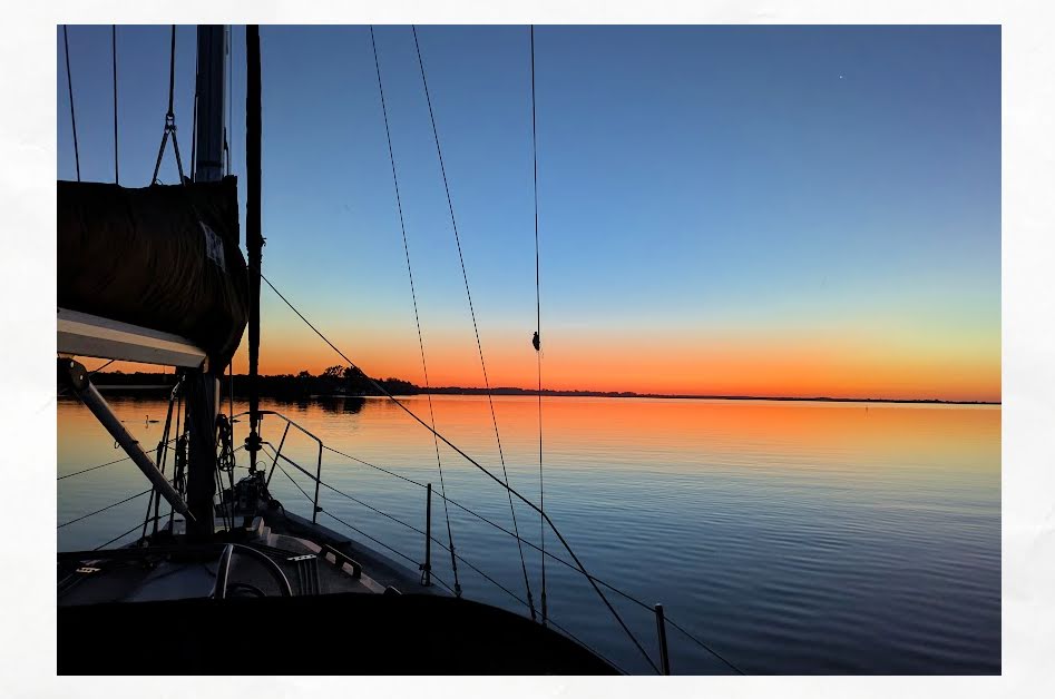 sunset at anchor from bow of sailboat 